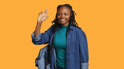 Enthusiastic african american student raising hand up to answer question, excited to tell teacher explanation to question in class, isolated over studio background, camera A