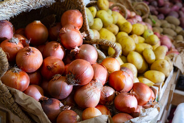 Potatoes and onion in crates and baskets at the grocery store