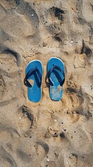Fototapeta premium A pair of flip flops is laying on the sand 