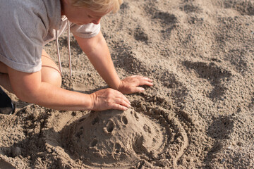 woman enjoys the morning fresh air on the sandy shore and builds a castle from wet sand, relaxing at sea on vacation, summer atmosphere