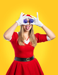 Young woman Santa Claus with two purple Christmas balls in her eyes sticking out her tongue