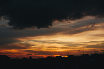 Dramatic sunset clouds and silhouette roof with antennas