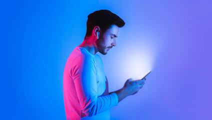 Glow of phone in hands of guy with wireless headphones, free space, profile © Prostock-studio
