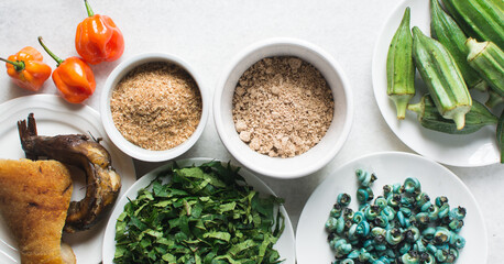 Overhead view of ingredients for making ogbono soup on a granite countertop, top view of mise en place of ingredients for making ogbono and okro soup, process of making nigerian ogbono soup