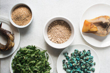 Overhead view of ingredients for making ogbono soup on a granite countertop, top view of mise en place of ingredients for making ogbono and okro soup, process of making nigerian ogbono soup