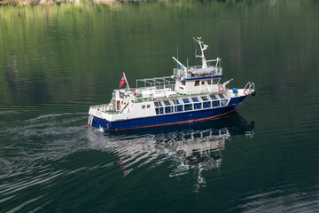 Obraz premium A Local Ferry Reflected in the Waters of Geiranger Fjord, Norway