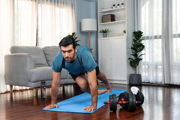 Athletic and sporty man doing mountain climber on fitness mat during home body workout exercise...