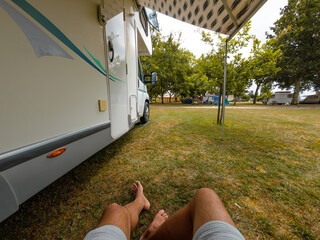 Relaxing sitting under the awning on the grass outside the motor home in the camping vertical shot
