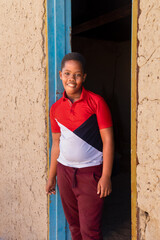 village portrait of a single african boy standing in front of the house