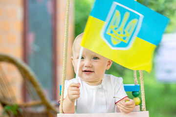 Young Child Holding Ukrainian Flag on a Swing