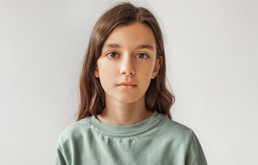 Fototapeta premium Portrait Of Serious Preteen Girl Standing Looking At Camera Over Gray Studio Background. Calm Kid Posing Wearing Casual Clothes, Headshot. Children Fashion Concept. Front View
