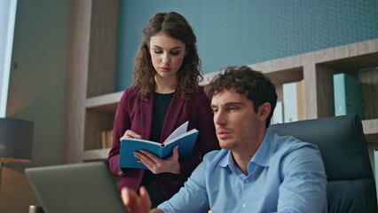 Woman mentor checking work man trainee in corporate office. Couple colleagues