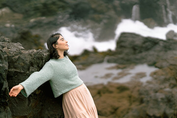 Young woman relaxing on a rocky beach in winter