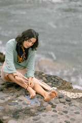 Woman putting on anklet on a winter beach