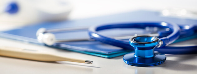 卓上にある聴診器、カルテ、体温計、血圧計。 医療、病院、健診のイメージ	