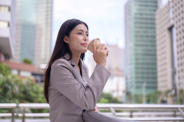 Beautiful businesswoman enjoying a coffee break outdoors in a modern city environment.