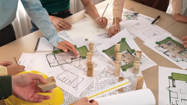 Architect and safety engineer discussion about building construction use blueprint on table with architectural document, measurement tool and wooden block scatter around at modern office. Delineation.
