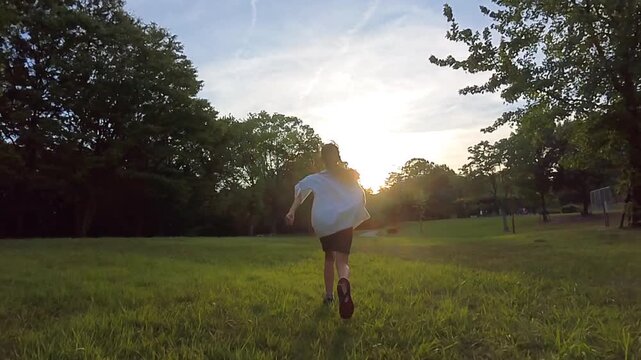 スローモーションで撮影した夏の公園で元気で走る小学生の子供の様子