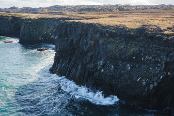 The rugged cliffs of Arnarstapi on Iceland's Snafellsnes Peninsula feature unique basalt columns...