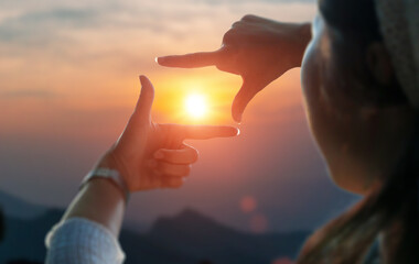Close up of female hands making frame gesture view distant over sunset. Future planning idea...