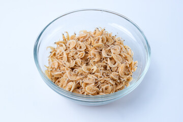 Selective focus of raw rebon shrimp in a clear bowl isolated on white background. Perfect for recipes, articles or any cooking content.