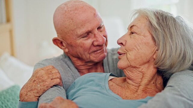 Senior couple, hug and kiss in bedroom, care and conversation together at home. Love, elderly man and happy woman in bed, embrace and connection for support, relationship and commitment to marriage