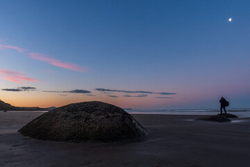 Sunrise at Moeraki Boulders with a silhouette of photographer