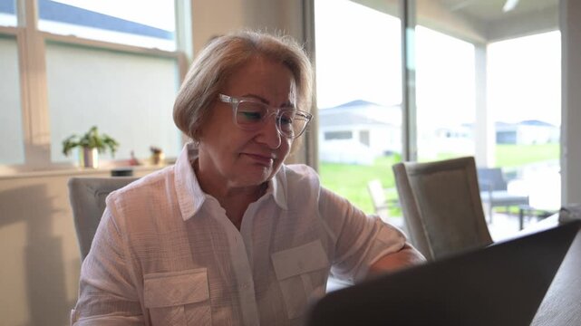 older senior citizen comes to terms with the news concerning a relative while reading her email in the morning on her laptop computer