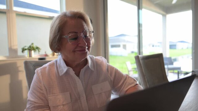 senior woman smiles in approval while reading the results on a computer screen