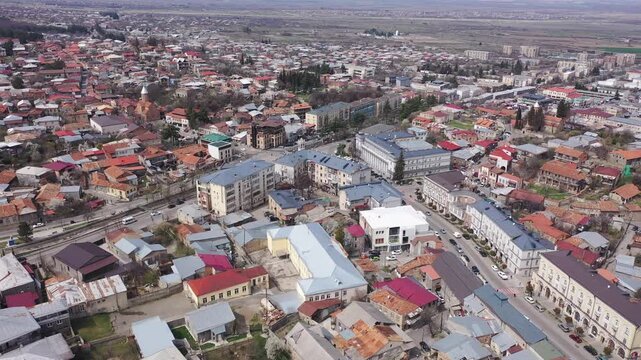 Scenic view from drone of central area of Telavi city overlooking large avenue with modern buildings surrounded by old small houses on spring day, Georgia