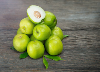 Green fresh jojobas lie in a heap on a wooden background