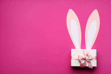 Paper bunny ears and gift box on pink background
