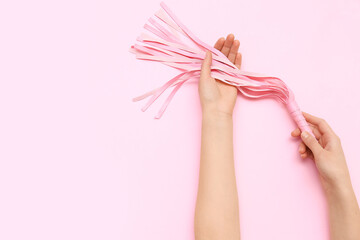 Woman with whip from sex shop on pink background