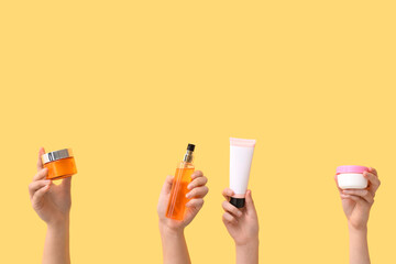 Female hands with different cosmetic products on yellow background