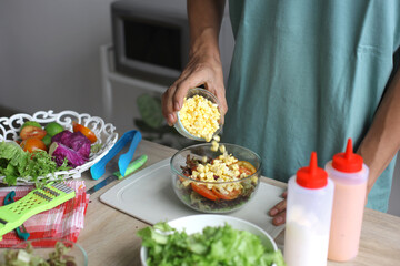 Man Making Salad, Putting Corn Into Bowl For Salad Ingredient Mixup