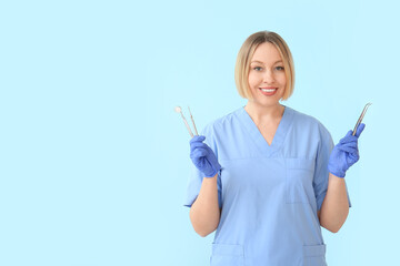 Female dentist with tools on blue background