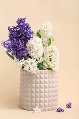Vase with beautiful hyacinth flowers on beige background