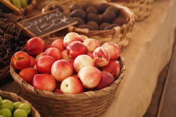 A beautiful display of fresh, ripe nectarines in a rustic woven basket at a local farmers market