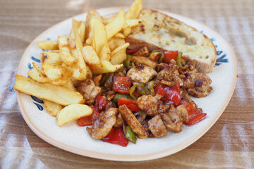 A plate filled with Delicious Chicken StirFry accompanied by Chips and Garlic Bread