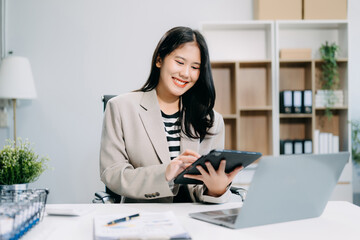 Business woman using tablet and laptop for doing math finance on an office desk, tax