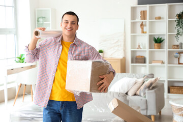 Young man with stretch wrap and cardboard box at home