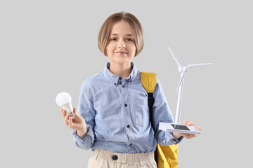 Teenage boy with wind turbine model and light bulb on light background. Ecology concept
