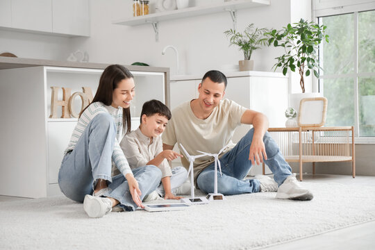 Happy family with wind turbine models and portable solar panel in kitchen