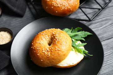 Plate of tasty bagels with butter and arugula on blue wooden background