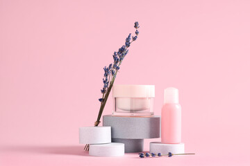 Decorative podiums with different cosmetic products and lavender flowers on pink background