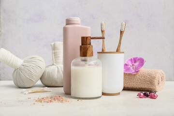 Bottles of cosmetic product and bath supplies on light background