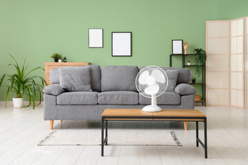 Electric fan on wooden coffee table in interior of stylish living room