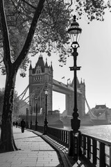 Black and White Photo of Tower Bridge in London with a Lamppost and Pedestrian © talkative.studio