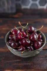 Ripe red cherries in a bowl on a wooden table