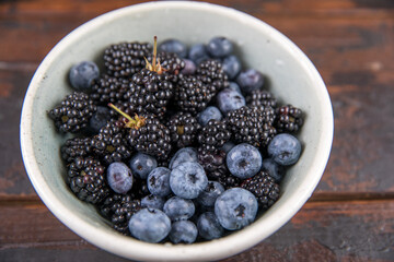 Ripe black blackberries and blue blueberries on a wooden table